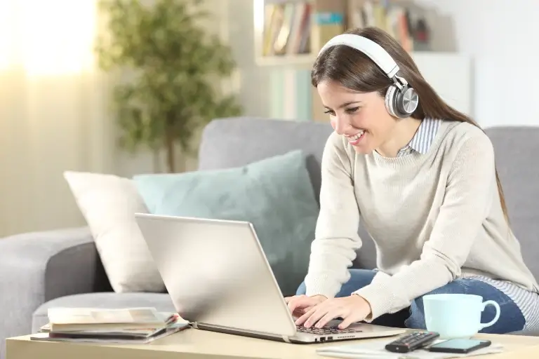 Lächelnde Frau mit Kopfhörern vor dem Laptop