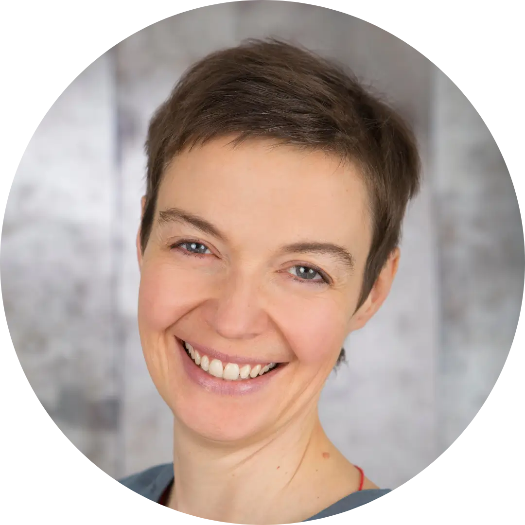 Porträt der lächelnden Gerlinde Geiss-Mayer mit kurzem braunen Haar vor einem neutralen, unscharfen Hintergrund