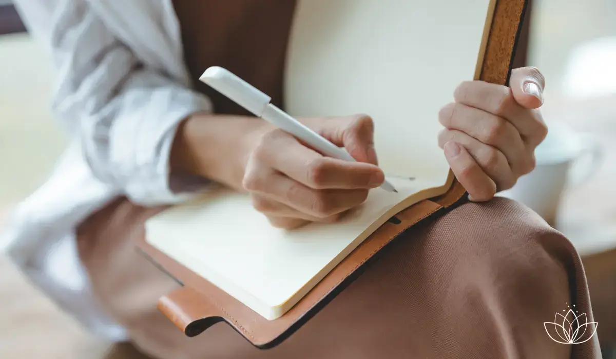 Person schreibt mit der Hand in ein Notizbuch – Sinnbild für die schriftliche Reflexion der eigenen Praxis