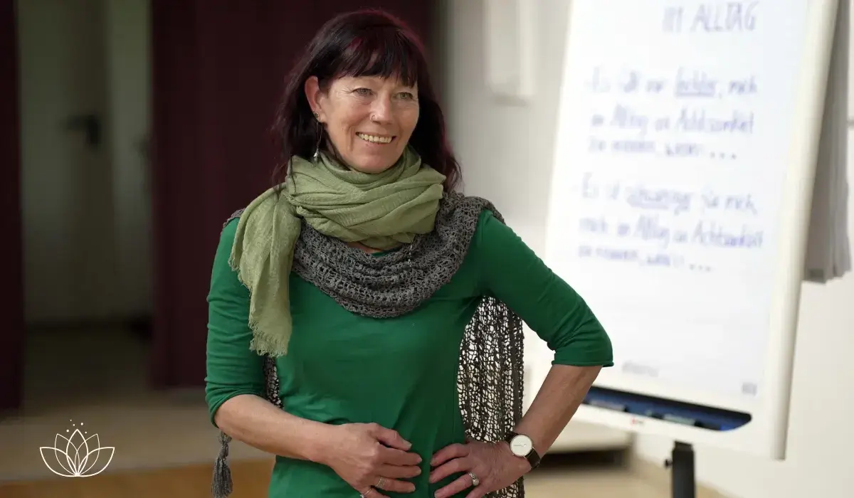 Achtsamkeitstrainerin steht lächelnd neben einem Flipchart mit Notizen zu Achtsamkeit im Alltag